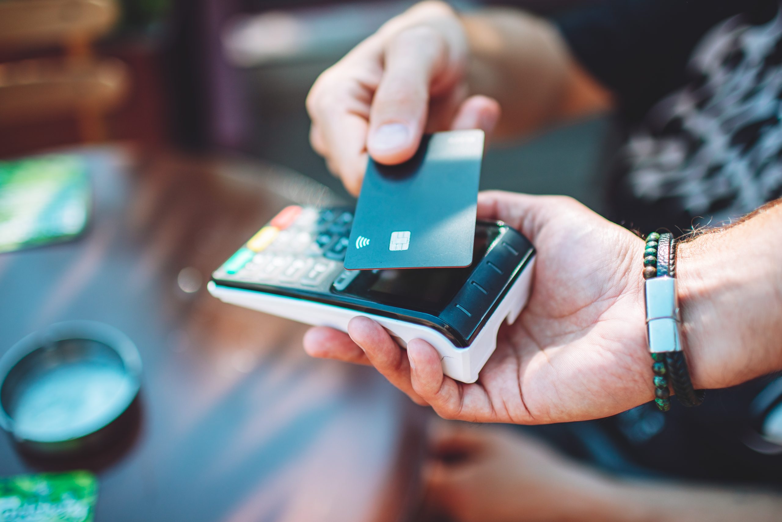 Adult man paying with credit card at cafe, close up of hands with credit card and credit card reader Homem adulto pagando com cartão de crédito em uma cafeteria, close up das mãos com cartão de crédito e leitor de cartão de crédito
